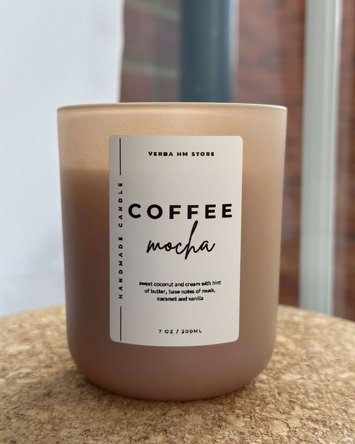 Candle labeled 'Coffee Mocha' on a textured surface with a blurred background