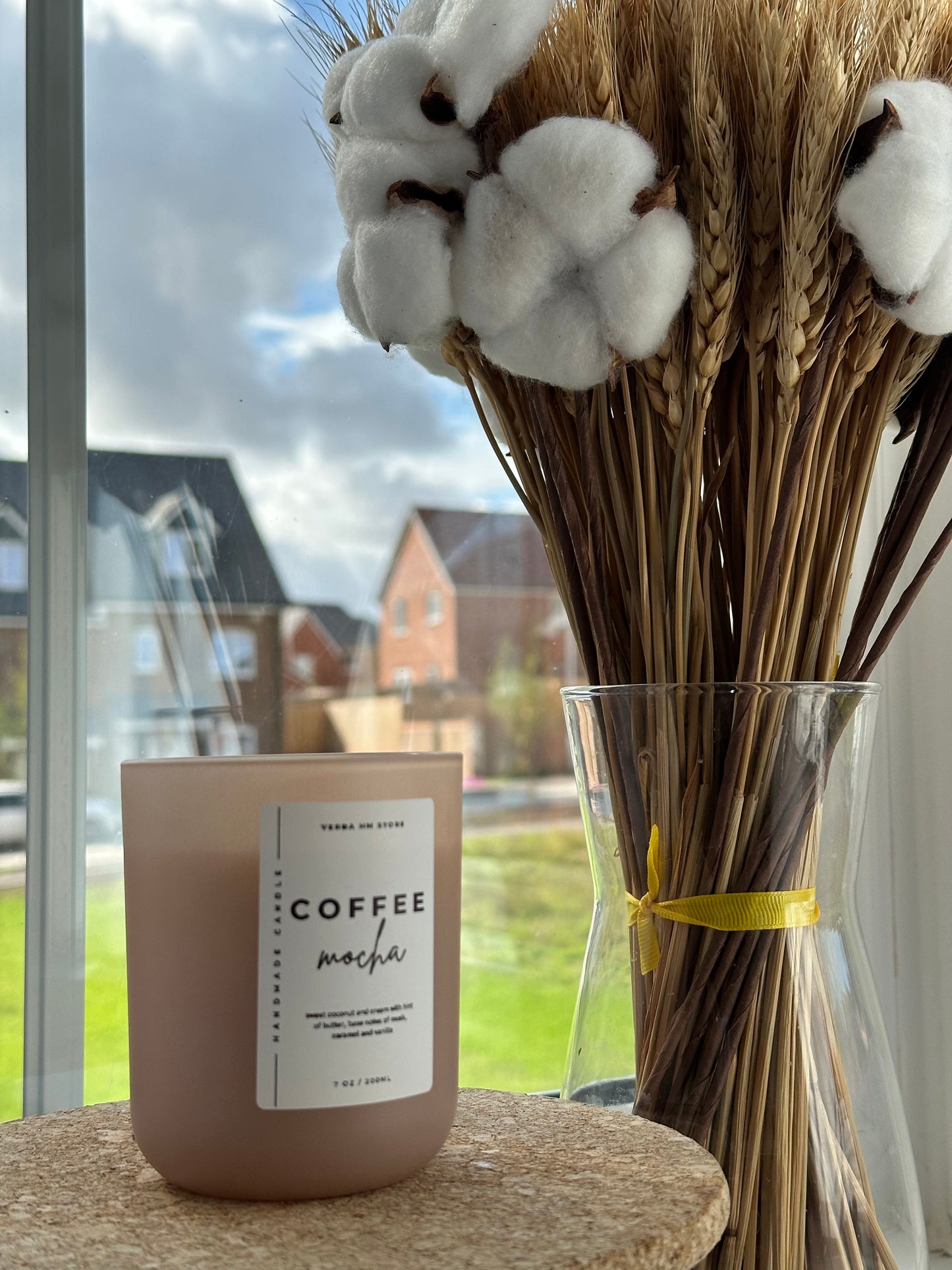 Candle labeled 'Coffee mocha' with decorative sticks and cotton balls on the background.
