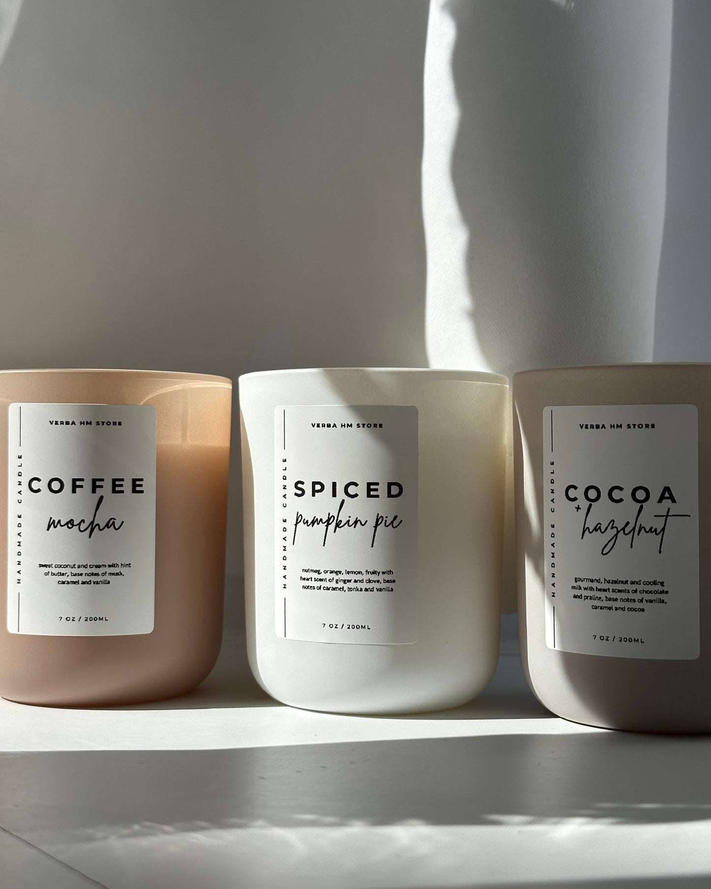 Three candles with labels on a white surface